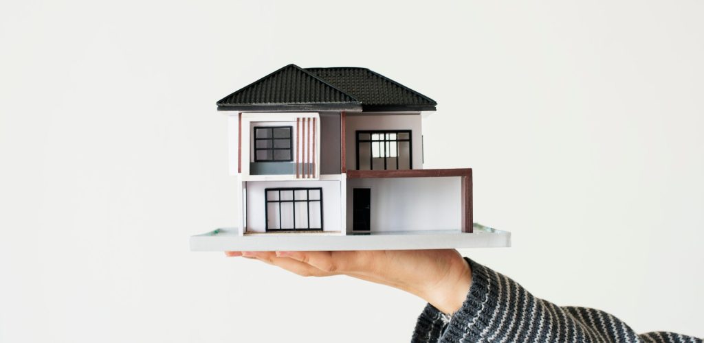 House loan concept isolated on white background Hand presenting model house for home loan campaign